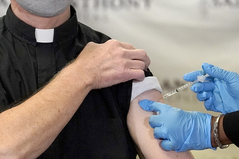 A Catholic priest receives the first of the two Pfizer-BioNTech covid-19 vaccinations at a hospital in Chicago in this Dec. 23 photo. In a growing consensus, religious leaders at the forefront of the anti-abortion movement in the United States are telling their followers that the leading vaccines available to combat covid-19 are acceptable to take, given their remote and indirect connection to lines of cells derived from aborted fetuses.
(AP/Charles Rex Arbogast)