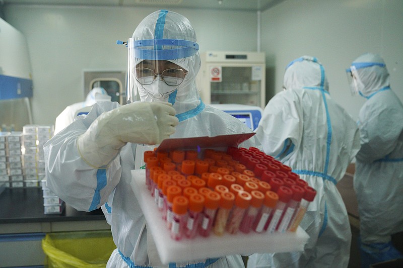 In this photo released by Xinhua News Agency, Yang Hongke checks on test samples at a testing lab of KingMed Diagnostics Group Co., Ltd. in Shijiazhuang in northern China's Hebei Province on Saturday, Jan. 9, 2021. Chinese health authorities say scores more people have tested positive for coronavirus in Hebei province bordering on the capital Beijing. The outbreak focused on the Hebei cities of Shijiazhuang and Xingtai is one of China's most serious in recent months and comes amid measures to curb the further spread during next month's Lunar New Year holiday. (Mu Yu/Xinhua via AP)