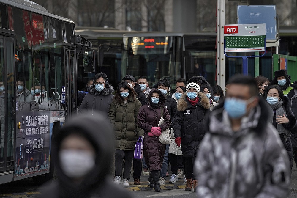 People wearing face masks to help curb the spread of the coronavirus walk out from a bus station for the traveller from the outskirts of Beijing on Monday, Jan. 11, 2012. Chinese health authorities say scores more people have tested positive for coronavirus in Hebei province bordering on the capital Beijing. The outbreak focused on the Hebei cities of Shijiazhuang and Xingtai is one of China's most serious in recent months and comes amid measures to curb the further spread during next month's Lunar New Year holiday. (AP Photo/Andy Wong)