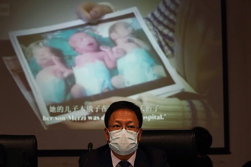 Xu Guixiang, a deputy spokesperson for the Xinjiang regional government, looks up near a slide showing a photo of Uighur infants during a press conference to refute accusations of genocide in Beijing, China. The Chinese official on Monday denied Beijing has imposed coercive birth control measures among Muslim minority women, following an outcry over a tweet by the Chinese Embassy in Washington claiming that government polices had freed women of the Uighur ethnic group from being "baby-making machines." (AP Photo/Ng Han Guan) story.lead_photo.caption