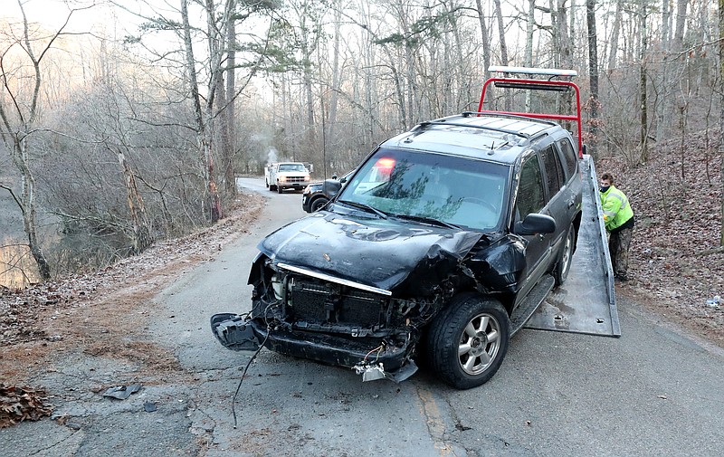 A wrecker service employee loads a 2004 GMC Envoy onto a flatbed in the 100 block of Sleepy Valley Road Tuesday morning. - Photo by Richard Rasmussen of The Sentinel-Record story.lead_photo.caption