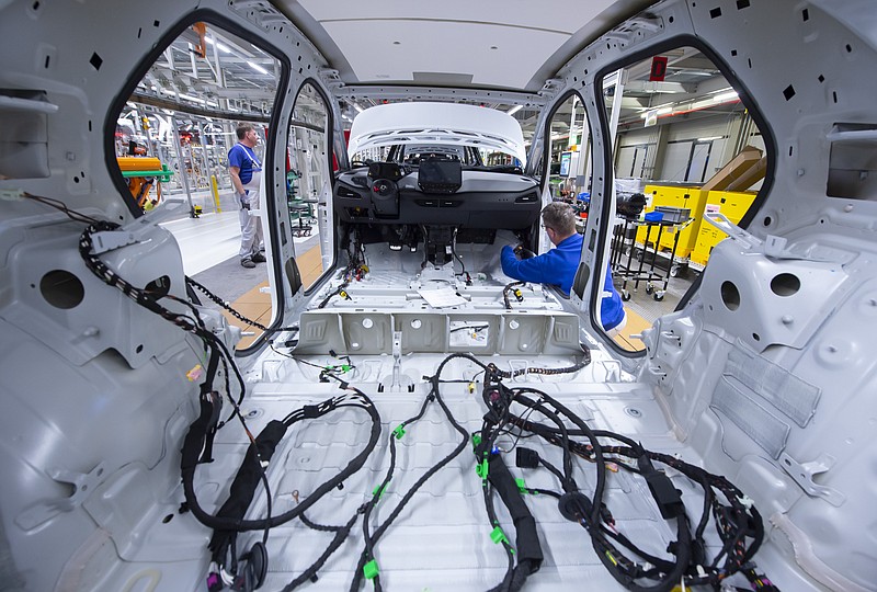 FILE - In this Tuesday, Feb. 25, 2020 file photo, a worker completes an electric car ID.3 body at the assembly line, during a press tour at the plant of the German manufacturer Volkswagen AG, VW, in Zwickau, Germany. Automaker Volkswagen tripled sales of battery-only cars last year as its new electric compact ID.3 came on the market ahead of tough new limits on auto emissions. (AP Photo/Jens Meyer, file)