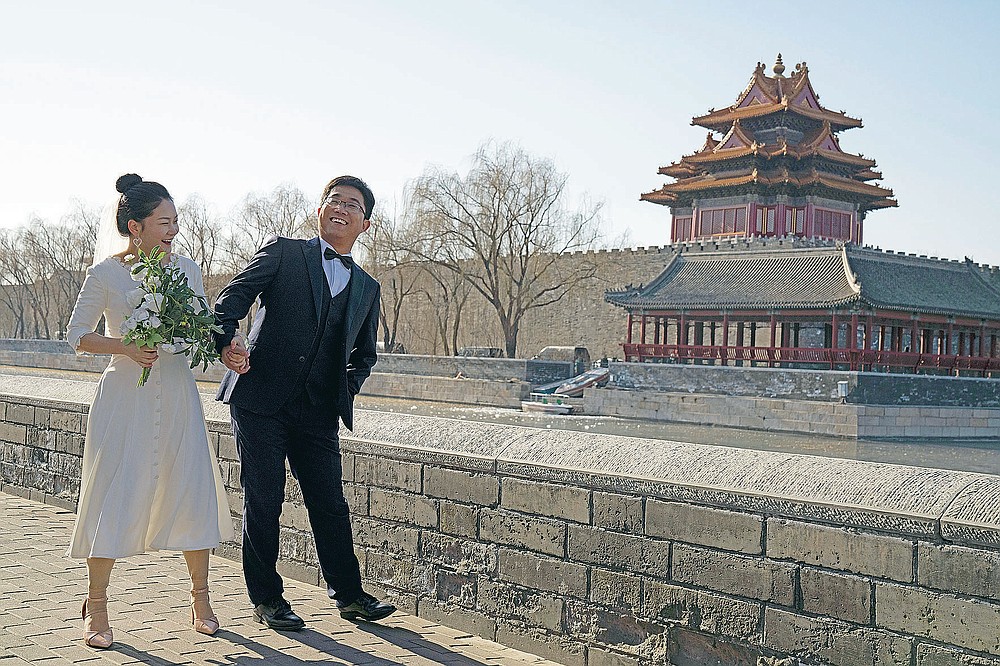 Le marié Dong Yangfeng et la mariée Wang Sai posent pour des photos près de la Cité Interdite à Pékin le dimanche 20 décembre 2020. Les inséparables en Chine adoptent un sentiment de normalité alors que la pandémie COVID semble être sous contrôle dans le pays où elle a été la première détecté. (Photo AP / Ng Han Guan)