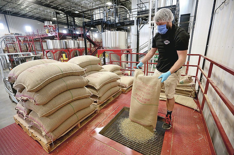 Kyle Hoppman pours green coffee beans into a roaster at Verena Street Coffee Co. in Dubuque, Iowa, on Thursday, Dec. 3, 2020. The company is celebrating its 10-year anniversary.  (Jessica Reilly/Telegraph Herald via AP)