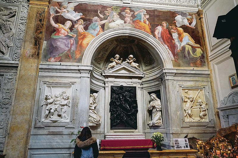 A woman admires the 1514 fresco "Sybils receiving instruction from Angels" by Italian High Renaissance master painter Raffaello Sanzio, known as Raphael, adorns the inside of Santa Maria della Pace church, in Rome, Monday, Dec. 14, 2020. Like elsewhere in Europe, museums and art galleries in Italy were closed this fall to contain the spread of COVID-19, meaning art lovers must rely on virtual tours to catch a glimpse of the treasures held by famous institutions such as the Uffizi in Florence and the Vatican Museums in Rome. However, some exquisite gems of Italy's cultural heritage remain on display in real life inside the country's churches, some of which have collections of renaissance art and iconography that would be the envy of any museum. (AP Photo/Andrew Medichini)