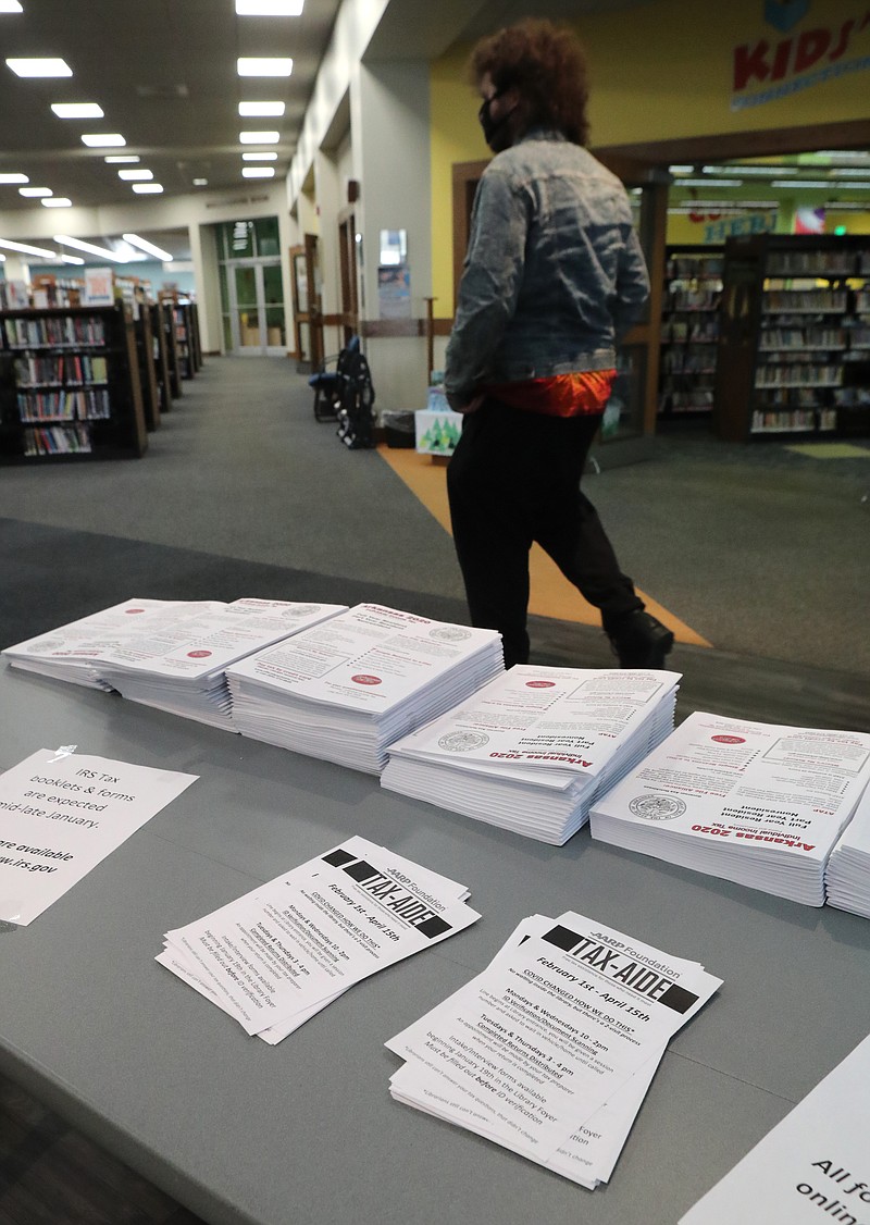 A patron walks past a table with tax forms and AARP Tax-Aide flyers at the Garland County Library on Thursday. - Photo by Richard Rasmussen of The Sentinel-Record