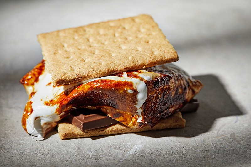 First printed in a Girl Scouts' handbook in 1927, the classic s'more has you toast a marshmallow on a stick over a campfire and then slide it off atop a piece of chocolate between two graham crackers. (For The Washington Post/Tom McCorkle)