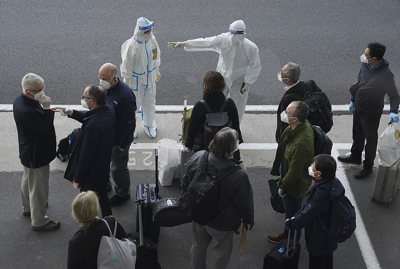A worker in protective coverings directs members of the World Health Organization (WHO) team on their arrival at the airport in Wuhan in central China's Hubei province on Thursday. A global team of researchers arrived Thursday in the Chinese city where the coronavirus pandemic was first detected to conduct a politically sensitive investigation into its origins amid uncertainty about whether Beijing might try to prevent embarrassing discoveries. - AP Photo/Ng Han Guan