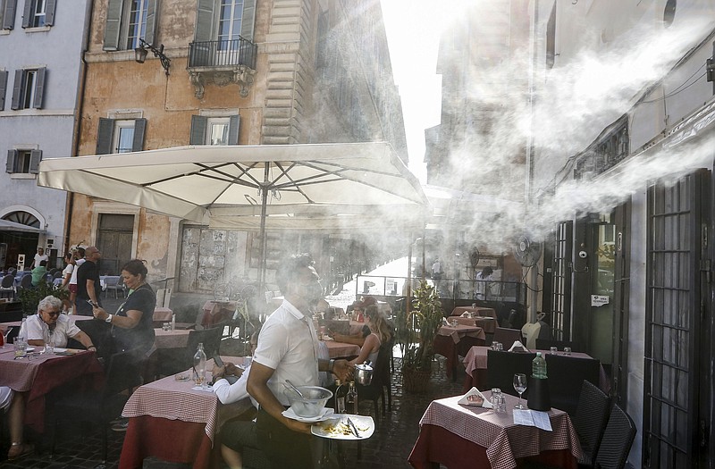 In this July 31, 2020, file photo, a fan sprays water mist as customers sit outside a cafe in downtown Rome during a heat wave with temperatures over 34 Celsius (104 Fahrenheit). - AP Photo/Riccardo De Luca