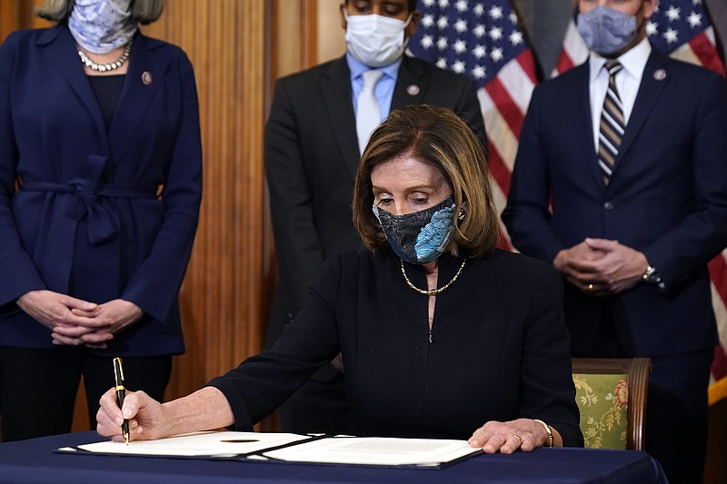 House Speaker Nancy Pelosi of Calif., signs the article of impeachment against President Donald Trump in an engrossment ceremony before transmission to the Senate for trial on Capitol Hill, in Washington, Wednesday, Jan. 13, 2021. (AP Photo/Alex Brandon)