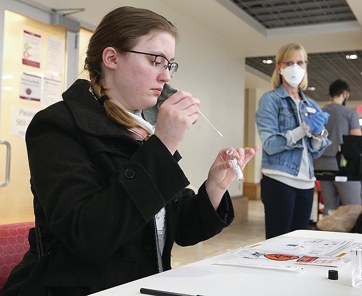 University of Arkansas at Little Rock graduate student Rebekah White puts her swab in a container after taking a covid-19 self-test as nurse Tracy England (right) looks on Thursday, Jan. 14, 2021, at the UALR Donaghey Student Center. UALR is offering surveillance testing for employees and students to identify asymptomatic coronavirus cases and determine the positivity rate for on-campus employees and students. (Arkansas Democrat-Gazette/Thomas Metthe)