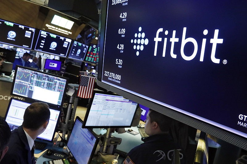 FILE - In this Oct. 28, 2019 file photo, the logo for fItbit appears above a trading post on the floor of the New York Stock Exchange.  Google has completed its $2.1 billion acquisition of fitness-gadget maker Fitbit. It's a deal that could help the internet company grow even stronger while U.S. government regulators pursue an antitrust case aimed at undermining its power. Thursday, Jan. 14, 2021 completion of the acquisition comes 14 months after Google announced a deal that immediately raised privacy alarms.   (AP Photo/Richard Drew, File)