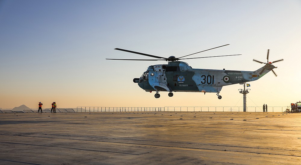 This image released Thursday, Jan. 14, 2021, by the Iranian Army shows a helicopter hovering over the Iranian-made Makran logistics vessel during a naval drill. Iran fired cruise missiles Thursday as part of the drill in the Gulf of Oman, state media reported, amid heightened tensions with the U.S. (Iranian Army via AP)