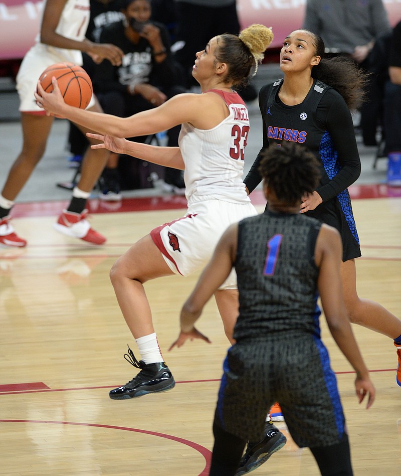 Arkansas guard Chelsea Dungee (33) reaches to score past Florida forward Jordyn Merritt, right, and guard Kiara Smith (1) during the first half of Thursday's game in Bud Walton Arena in Fayetteville. - Photo by Andy Shupe of NWA Democrat-Gazette