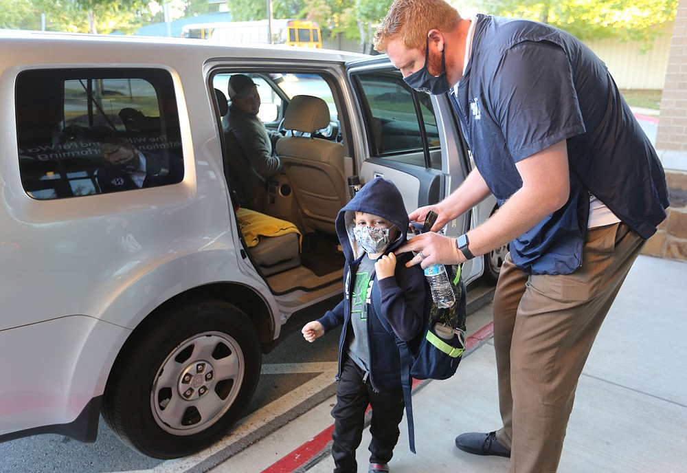 John Gourlay, director of development at The New School, helps Logan Patrick, a first grade student, with his back pack Thursday, October 1, 2020, as he enters the school for a day of classes in Fayetteville. Check out nwadg.com/photos for a photo gallery.(NWA Democrat-Gazette/David Gottschalk)