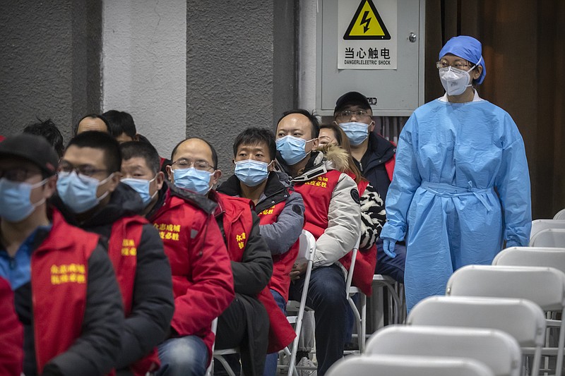 A medical worker wearing protective equipment monitors patients after they received the coronavirus vaccine at a vaccination facility in Beijing, Friday, Jan. 15, 2021. A city in northern China is building a 3,000-unit quarantine facility to deal with an anticipated overflow of patients as COVID-19 cases rise ahead of the Lunar New Year travel rush. (AP Photo/Mark Schiefelbein)