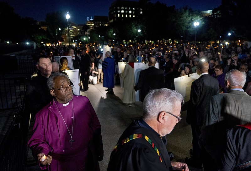 FILE - In this May 24, 2018, file photo, The Most Rev. Michael Curry, left, the presiding bishop of the U.S. Episcopal Church and others take part in a candlelight vigil outside the White House in Washington. As a nation shaken by political divisions prepares to inaugurate a new president on Wednesday, a group of Christian leaders, including Curry, are preparing to meet the tense moment with prayer during three days of ecumenical, nonpartisan programming organized under the umbrella of #PeaceWithJustice. - AP Photo/Andrew Harnik
