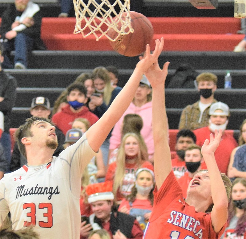 RICK PECK/SPECIAL TO MCDONALD COUNTY PRESS McDonald County center Teddy Reedybacon takes a rebound away from Seneca's Cooper Long during the Mustang's 66-23 win on Jan. 15 at MCHS.