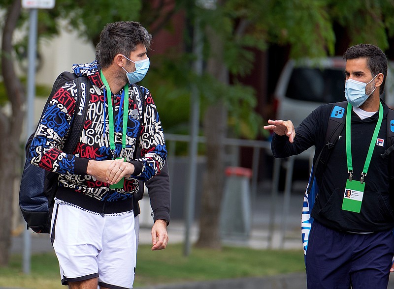 Italian tennis player Simone Bolelli, left, and Argentina's Maximo Gonzalez are escorted to their training session in Melbourne, Australia, Monday, Jan. 18, 2021. The number of players in hard quarantine swelled to 72 ahead of the Australian Open after a fifth positive coronavirus test was returned from the charter flights bringing players, coaches, officials and media to Melbourne for the season-opening tennis major. (Luis Ascui/AAP Image via AP)