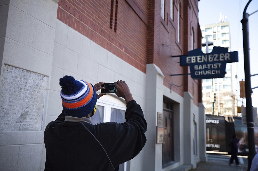 A man takes a photo of the Historic Ebenezer First Baptist Church where Martin Luther King Jr. preached on Monday, Jan. 18, 2021, in Atlanta. (AP Photo/Branden Camp)