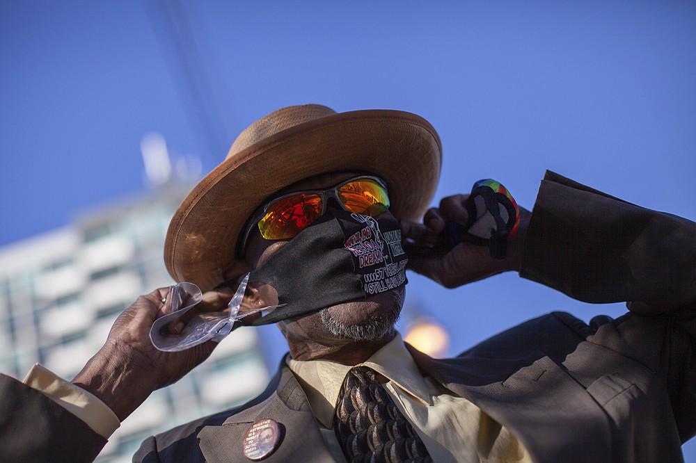 Anthony Wilson puts on a MLK mask on Dr. Martin Luther King Jr. Day, Monday, Jan. 18, 2021, in Atlanta. (AP Photo/Branden Camp)