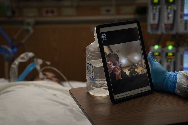 Sonya Rodriguez wipes her tears after seeing her father, who is in a covid-19 unit at Providence Holy Cross Medical Center in Los Angeles, via video chat arranged by chaplain Kevin Deegan on Jan. 9.
(AP/Jae C. Hong)