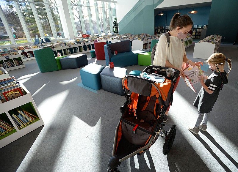 Renee Buckley of Fayetteville and her daughter, Campbell Buckley, 5, look at books Tuesday, in the children's section of the Fayetteville Public Library on the first day that the library has been open since its renovation and expansion. Voters in 2016 approved a property tax increase to help pay for the nearly $50 million expanded library's construction, which brings the building's size up to about 170,500 square feet. Library administrators opened to the public for the first time since late September, limiting the number of patrons to 200 at a time out of concern for the coronavirus pandemic. (NWA Democrat-Gazette/Andy Shupe)