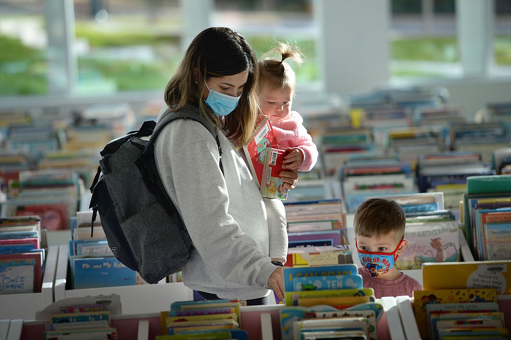 Tori Burge (left) of Fayetteville holds her daughter, Millie Burge, 1, as they and her son, Micah Burge, 3, look at books Tuesday in the children’s section of the Fayetteville Public Library on the first day that the library has been open since its renovation and expansion. Voters in 2016 approved a property tax increase to help pay for the nearly $50 million expanded library's construction, which brings the building's size up to about 170,500 square feet. Library administrators opened to the public for the first time since late September, limiting the number of patrons to 200 at a time out of concern for the coronavirus pandemic. Visit nwaonline.com/210120Daily/ for today's photo gallery.