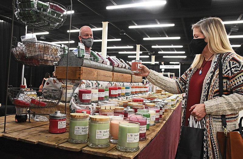 James Brooks, co-owner of Rock Creek Candles, chats with Kristina Davis of Orlando, Fl. as she shops Sunday, Dec. 6, 2020 during the Arkansas Craft Guild‚Äôs 42nd Annual Christmas Showcase in the Hall of Industry at the Arkansas State Fair Complex in Little Rock. See more photos at arkansasonline.com/127showcase/.
(Arkansas Democrat-Gazette/Staci Vandagriff)