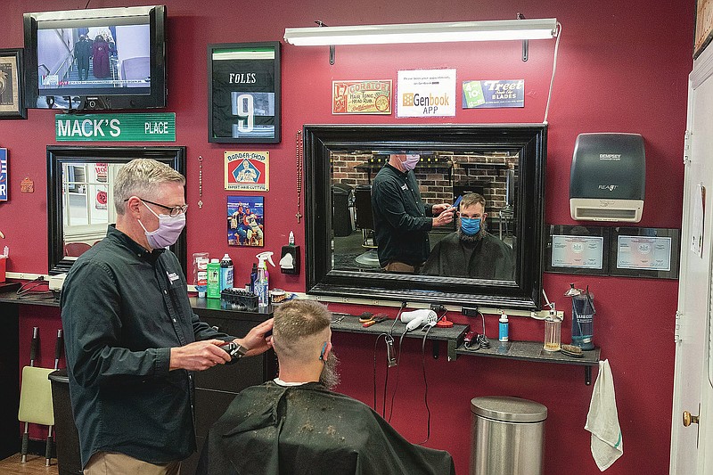 Former President Barack Obama and former first lady Michelle Obama are seen on a television screen as they arrive for the 59th Presidential Inauguration at the U.S. Capitol in Washington as barber Mark Mackrell gives a haircut to a regular at Mackell's Barber Shop, Wednesday, Jan. 20, 2021, in downtown Scranton, Pa. (AP Photo/Mary Altaffer)