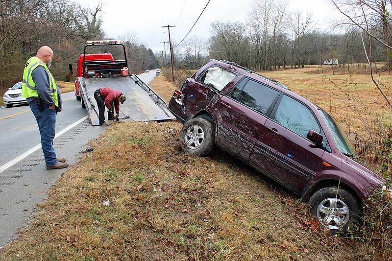 Fountain Lake Fire Chief Chris Farmer watches Alan Jester of Holcombs Transport and Recovery start to pull a vehicle out of a ditch on Park Avenue near Zeigler Road Thursday morning. - Photo by Tanner Newton of The Sentinel-Record