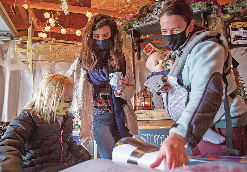Abbey Paxton hosts Megan Austin and her children Cora, 4, and Levi, 8 months, for a private shopping appointment at Storyhouse, a book store in the garage of her Windsor Heights home Wednesday, Dec. 23, 2020. (Zach Boyden-Holmes/The Des Moines Register via AP)