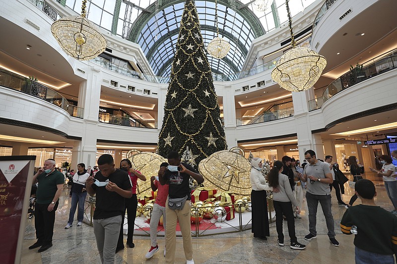 Tourists remove their masks to take photo in front of a giant Christmas tree at a shopping mall in Dubai, United Arab Emirates, Dec. 27, 2020. On Thursday, Jan 21, 2021, Dubai’s tourism authorities announced an immediate halt to all live music and shows at hotels and restaurants as coronavirus cases surged to unseen heights over recent weeks. The UAE also ordered the suspension of all non-urgent surgeries to deal with an influx of new COVID-19 patients. (AP Photo/Kamran Jebreili)