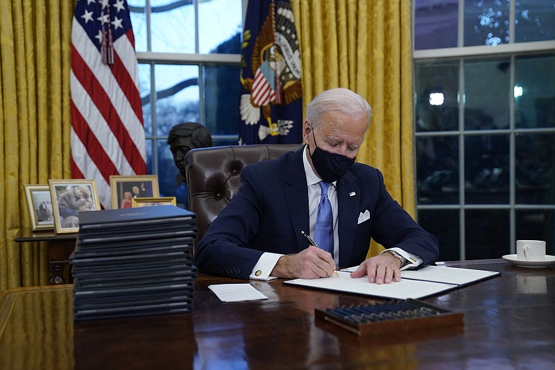 President Joe Biden signs his first executive orders in the Oval Office of the White House on Wednesday, Jan. 20, 2021, in Washington. (AP Photo/Evan Vucci)