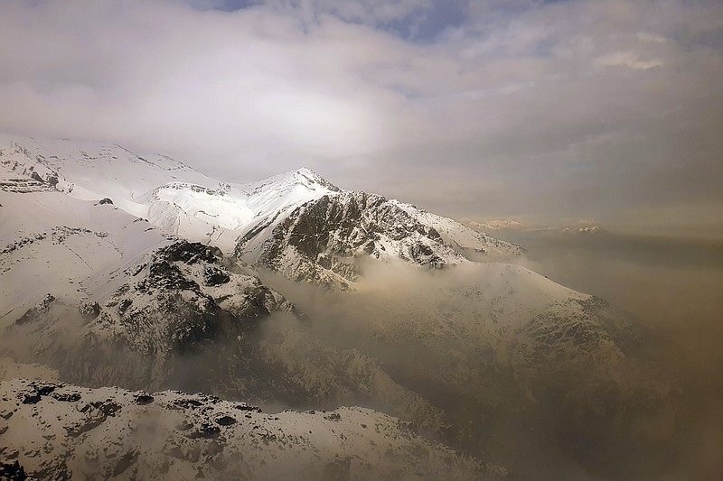 Air pollution blankets a mountain range in Tehran, Iran, Dec 23. Iran's capital and its major cities have been plunged into darkness as rolling outages in recent weeks left millions with no electricity for hours. With toxic smog blanketing the skies in Tehran and the country buckling under the strain of the pandemic and sanctions targeting Iran’s oil and gas industry, speculation about the spate of blackouts gripped social media. Soon, fingers pointed at an unlikely culprit: Bitcoin. - AP Photo/Ebrahim Noroozi