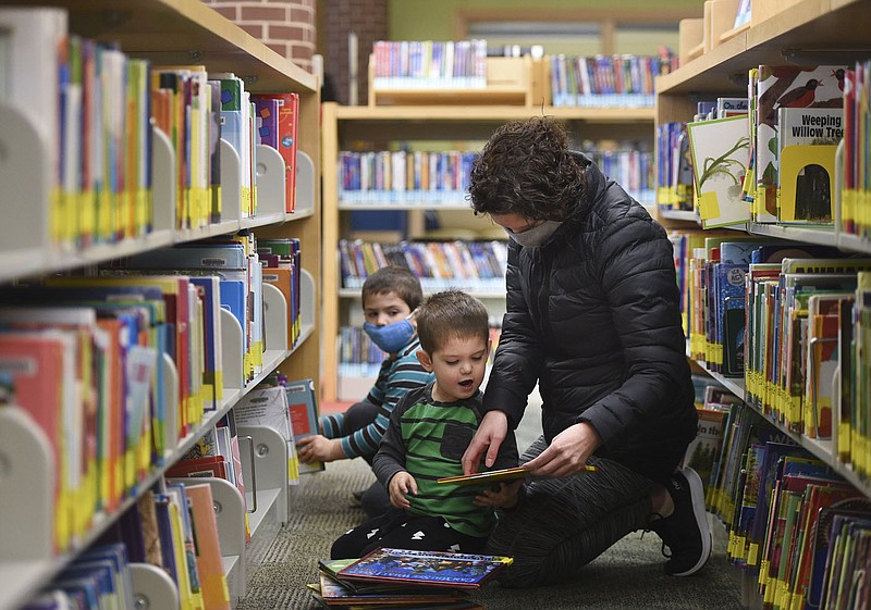 Danielle Sanders of Bentonville (right), picks out books with sons Henry Sanders, 4, (from left) and Tyler Sanders, 3, Thursday, January 21, 2021 at the Bentonville Library in Bentonville. Bentonville residents could be asked to approve $266 million in bonds for street and park improvements as well as other capital projects in the city. Library plans call for 6,400-square-foot addition and renovations to 10,000 square feet of the interior of the building. The addition would include a children's expansion, which would include a larger story time area and larger craft space. There would also be a teen space and maker space. Check out nwaonline.com/210119Daily/ for today's photo gallery. 
(NWA Democrat-Gazette/Charlie Kaijo)