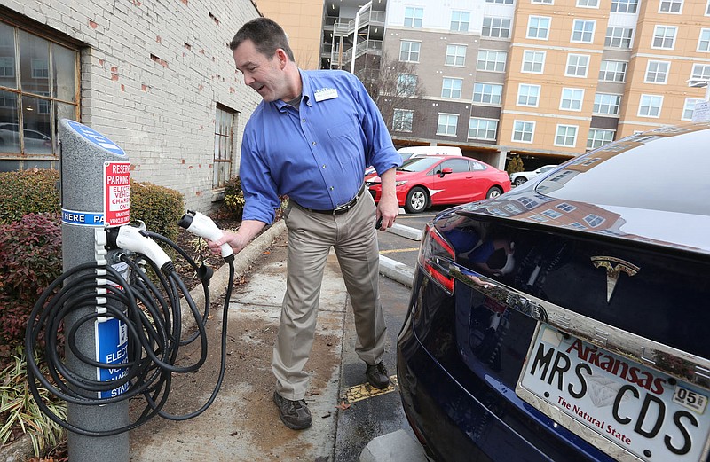 Mel Collier prepares to plug in his wife's car Thursday, January 21, 2021, for a charge at one of the electric charging stations in the parking lot of the Collier Drug Store on Dickson Street in Fayetteville. The city adopted regulations for businesses to follow when installing electric vehicle charging stations in their parking lots, such as minimum voltage, signs and fees. Check out nwaonline.com/210124Daily/ and nwadg.com/photos for a photo gallery.
(NWA Democrat-Gazette/David Gottschalk)