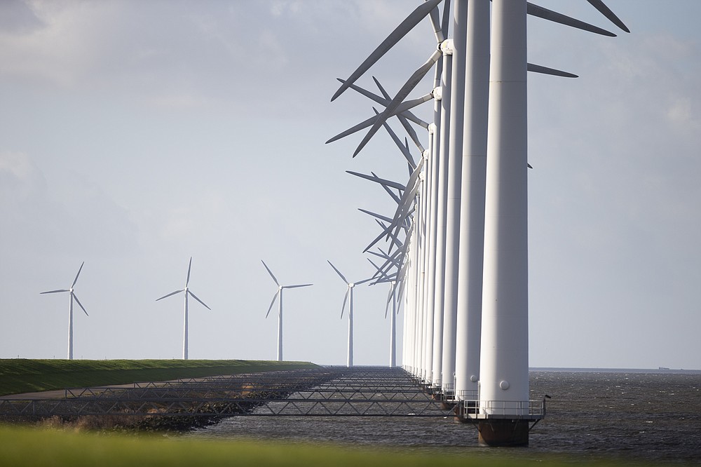 Wind turbines are seen on a dike near Urk, Netherlands, Friday, Jan. 22, 2021. A group of scientists, including five Nobel laureates, called Friday for more action to adapt the world to the effects of climate change, drawing comparisons with the faltering response to the coronavirus crisis, ahead of a major online conference on climate adaptation starting Monday and hosted by the Netherlands. (AP Photo/Peter Dejong)