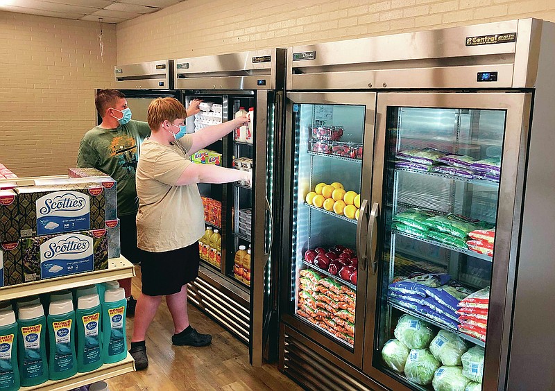In this provided by Anthony Love, Hunter Weertman, 16, left, works alongside a fellow student to stock the refrigerator in the student-led free grocery store at Linda Tutt High School on Nov. 20, 2020, in Sanger, Texas. The store provides food, toiletries and household items to students, faculty and community members in need. (Anthony Love via AP)