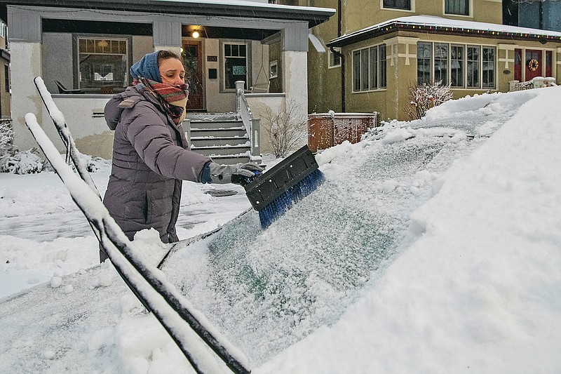 Sarah Lee clears snow off her vehicle in the Edgewater neighborhood, after a snowstorm in Chicago, Tuesday, Jan. 26, 2021.  In the Chicago area, between between 3 inches (7.6 centimeters) and 5 inches (12.7 centimeters) of snow had fallen by early Tuesday. (Tyler LaRiviere /Chicago Sun-Times via AP)