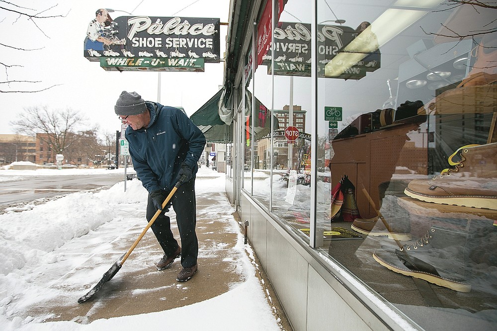 Tom Giamalva, owner of Palace Show Services, clears away snow from the sidewalk in front of his business on North Main Street on Tuesday, Jan. 26, 2021, after a snowstorm in Rockford, Ill. Many schools and businesses closed as the storm moved across the Midwest and officials urged drivers to stay off the roads. (Scott P. Yates/Rockford Register Star via AP)