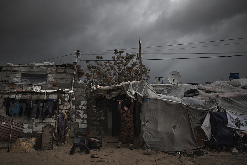 A Palestinian woman checks the nylon cover on the roof of her house on a rainy day in a poor neighborhood of Khan Younis, in the southern Gaza Strip, Wednesday, Jan. 20, 2021. (AP Photo/Khalil Hamra)