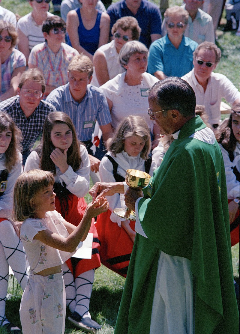 FILE - In this Spet. 19, 1988 file photo Rev. Joseph Hart dispenses communion during an outdoor Mass celebrated for participants of the Basque Festival in Buffalo, Wyo. On Tuesday, Jan. 26, 2020 the Vatican’s Congregation for the Doctrine of the Faith cleared retired Cheyenne, Wyoming Bishop Hart of seven accusations of abuse, determined that five others couldn’t be proven “with moral certitude” and that two cases involving boys, who were 16 and 17, couldn’t be prosecuted given the Catholic Church didn’t consider them minors at the time of the alleged abuse, the diocese said. (AP Photo/Dean Wariner, File)