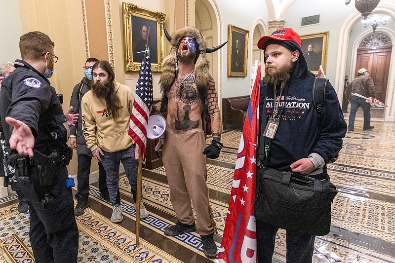 In this Jan. 6 file photo, supporters of President Donald Trump, including Jacob Chansley, center with fur and horned hat, are confronted by Capitol Police officers outside the Senate Chamber inside the Capitol in Washington. A video showed Chansley leading others in a prayer inside the Senate chamber. - AP Photo/Manuel Balce Ceneta