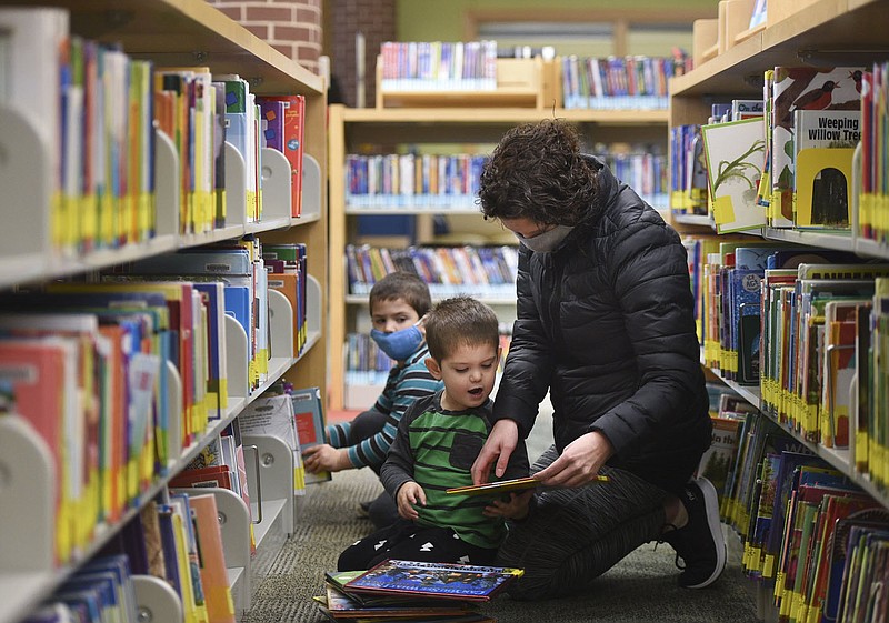 Danielle Sanders of Bentonville (right), picks out books with sons Henry Sanders, 4, (from left) and Tyler Sanders, 3, Thursday, January 21, 2021 at the Bentonville Library in Bentonville. Bentonville residents could be asked to approve $266 million in bonds for street and park improvements as well as other capital projects in the city. Library plans call for 6,400-square-foot addition and renovations to 10,000 square feet of the interior of the building. The addition would include a children's expansion, which would include a larger story time area and larger craft space. There would also be a teen space and maker space. 
(NWA Democrat-Gazette/Charlie Kaijo)