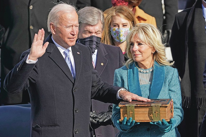 FILE - In this Wednesday, Jan. 20, 2021 file photo, Joe Biden is sworn in as the 46th president of the United States by Chief Justice John Roberts as Jill Biden holds the Bible during the 59th Presidential Inauguration at the U.S. Capitol in Washington. On Friday, Jan. 29, 2021, The Associated Press reported on stories circulating online incorrectly asserting Biden swore on a “Masonic/Illuminati” Bible during his inauguration. It is a Douay-Rheims Bible, an English translation of a Latin Bible, which has been in the Biden family since the 1890s. Robert Miller, professor of biblical studies at The Catholic University of America, says, “Nothing even vaguely Masonic would have been anywhere near these Bibles. … Same thing for the ‘Illuminati,’ to the extent that such a thing existed: repeatedly condemned by the Popes and certainly coming nowhere into contact with Catholic Bibles.” (AP Photo/Andrew Harnik)