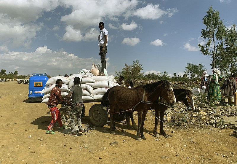 In this Tuesday Jan. 12, 2021 photo provided by the Catholic Relief Services, people affected by the conflict in Tigray load food aid provided by USAID and Catholic Relief Services onto a donkey cart to be tansported to their home, outside Mekele, Ethiopia. From “emaciated” refugees to crops burned on the brink of harvest, starvation threatens the survivors of more than two months of fighting in Ethiopia’s Tigray region. Authorities say more than 4.5 million people, or nearly the entire population, need emergency food. The first humanitarian workers to arrive after weeks of pleading with Ethiopia for access describe weakened children dying from diarrhea after drinking from rivers, and shops that were looted or depleted weeks ago. (Catholic Relief Services via AP)