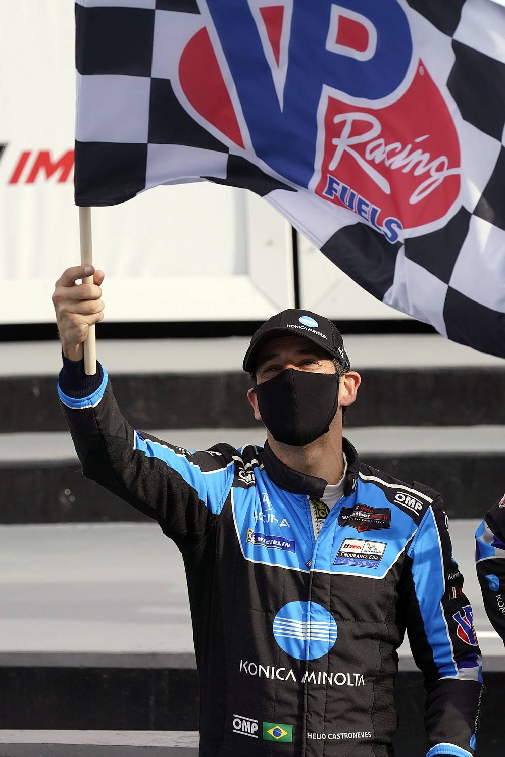 Helio Castroneves waves the checkered flag after he and driving teammates Ricky Taylor, Filipe Albuquerque and Alexander Rossi won the Rolex 24 hour auto race at Daytona International Speedway, Sunday, Jan. 31, 2021, in Daytona Beach, Fla. (AP Photo/John Raoux)