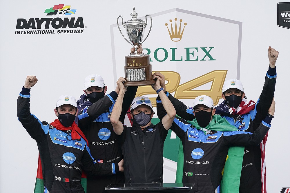 The Konica Minolta racing team, from left to right, Filipe Albuquerque, Alexander Rossi, team owner Wayne Taylor, Helio Castroneves and Ricky Taylor celebrate with the championship trophy after winning the Rolex 24 hour auto race at Daytona International Speedway, Sunday, Jan. 31, 2021, in Daytona Beach, Fla. (AP Photo/John Raoux)
