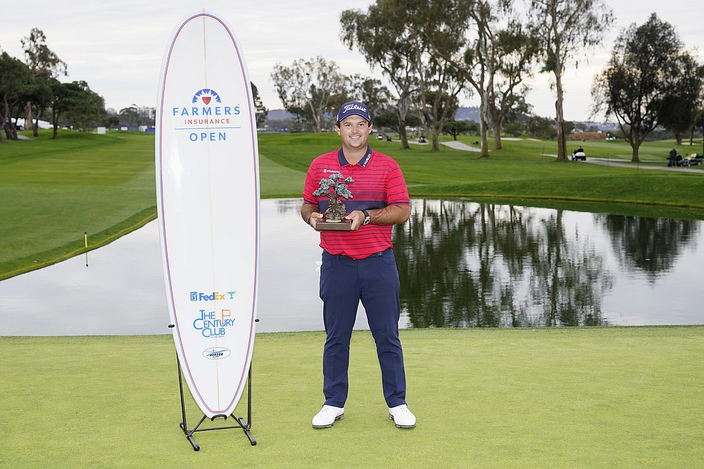 Patrick Reed stands on the South Course while holding his trophy for winning the Farmers Insurance Open golf tournament at Torrey Pines, Sunday, Jan. 31, 2021, in San Diego. (AP Photo/Gregory Bull)